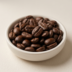 Illustrative close-up of dark-roasted coffee beans in a ceramic dish.