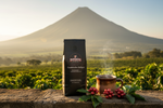 Pops Coffee Company Guatemalan Antigua bag on stone at a coffee farm with Agua volcano and ripe coffee cherries