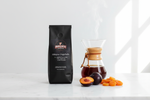 Pops Coffee Company Ethiopian Yirgachaffe bag on white marble with Chemex, vibrant amber coffee and fresh plums