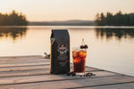 Pops Coffee Company Michigan Cherry bag on a Michigan lake dock at golden hour with cherry cold brew and fresh cherries