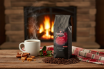 Pops Coffee Company Christmas Spirit bag on a festive holiday table beside a crackling fireplace with steaming mug