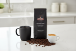 Pops Coffee Company Espresso Roast bag on a white kitchen counter with bold coffee, espresso cup with crema and roasted beans