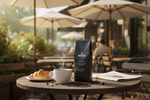 Pops Coffee Company Cafe Blend bag on an outdoor cafe patio table with steaming coffee and croissant