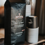 Pops House Blend bag on a cafe counter next to stacked cups